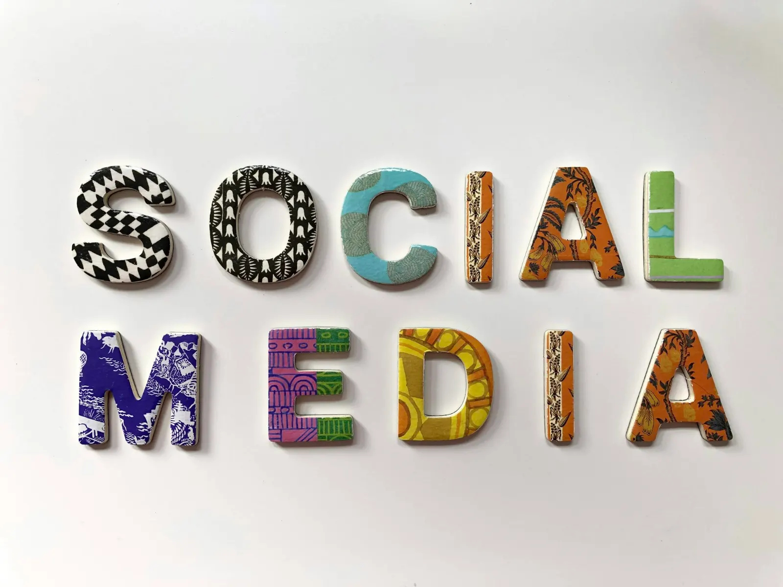 Bunt gemusterte Buchstaben bilden auf weißem Grund die Worte „Social Media“.